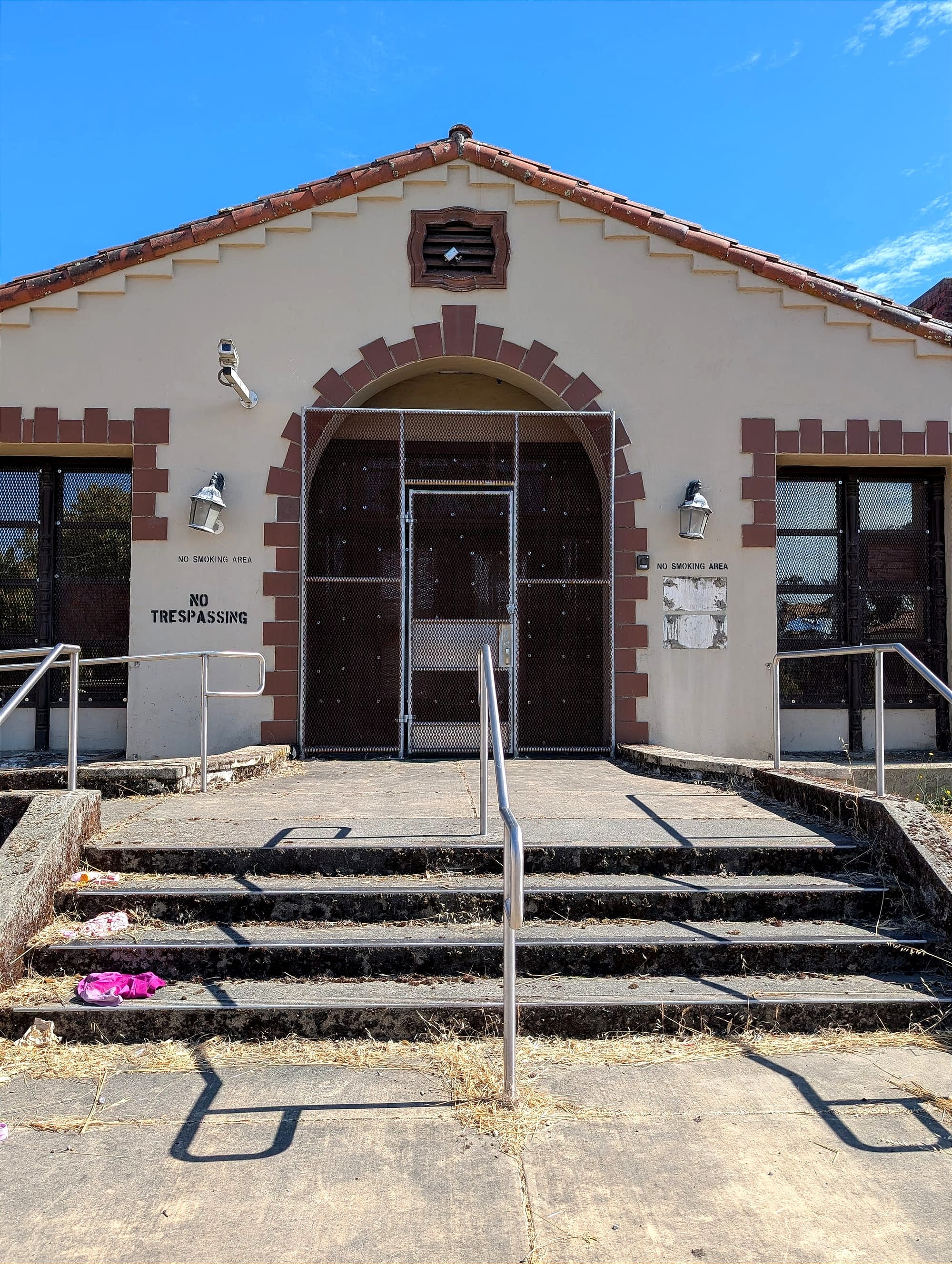 the entrance to an abandoned building with 'no trespassing' on it and garbage on the front stairs