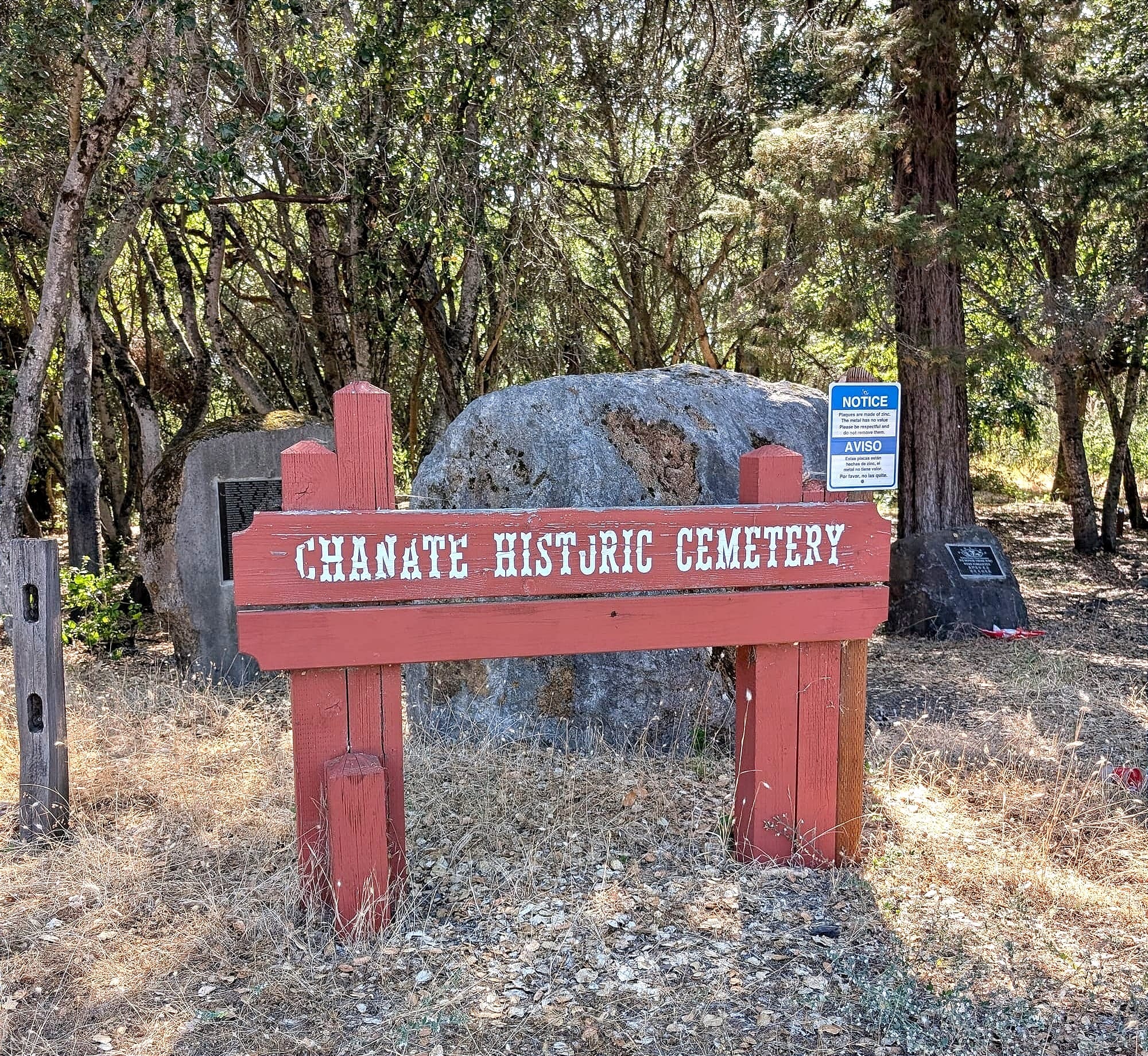 a wooden sign reads 'Chanate Historic Cemetery' in a wooded area