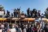 Several protesters hold signs on top of a bus. 