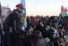 A man in sunglasses and a red beret standing in front of a crowd of people waving Indigenous and Palestinian flags.