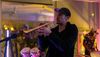 a man dressed in black with a black ballcap plays trumpet at a party