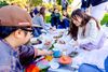 A group of people sit on blankets in a park having a picnic