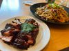 A plate of sticky smoked pork belly and a plate of cold peanut noodles.