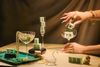 Mahjong tiles arranged in crystal coupes and a champagne flute alongside pearl necklaces, jade bangles, gold jewelry, a crystal swan, and a small gold Buddha.