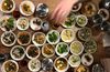 A wooden table is covered with small dishes filled with various foodstuffs.