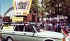 a car with a sign on it that reads 'lavender lounge, TV dance party for gay boys & girls' at a pride parade in SF)
