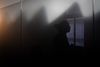 Woman standing in a space with her face obscured in shadow to preserve anonymity.