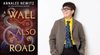 a sci-fi novel by Annalee Newitz called A Wall Is Also a Road, an author photo of a person smiling with dark short hair, round dark glasses, a yellow shirt, blue tie, and gray suit jacket