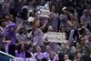 Basketball fans wearing lavender clothes show signs readings, "Ballhalla believes" and "Move the Hawks game Women = Prime time"