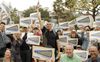 A man in a black shirt waving a campaign sign amid a group of people holding signs that say "Manny for Supervisor"