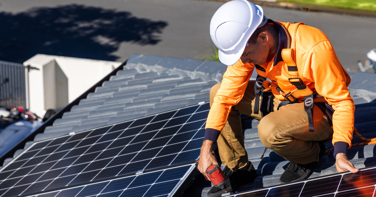 Integrador instala painéis solares no telhado, usando equipamento de segurança. A cena destaca a sustentabilidade e a economia de energia.