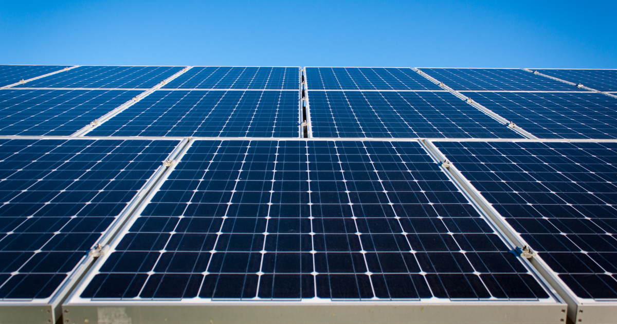 Conjunto de painéis solares alinhados, captando energia sob um céu azul limpo. A imagem destaca eficiência e sustentabilidade na geração de energia.