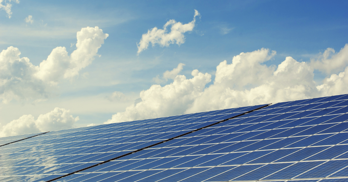 Painéis solares fotovoltaicos refletem a luz sob um céu azul com nuvens, destacando o potencial do mercado solar.