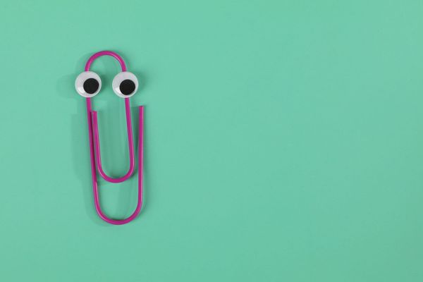 A purple paper clip that's slightly bent and has googly eyes pasted on sits atop a green background.