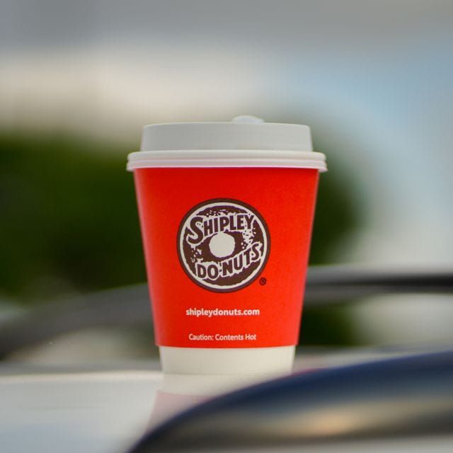 A red Shipley Do-Nuts hot-beverage cup printed with the words "Caution: Contents Hot" below the logo.