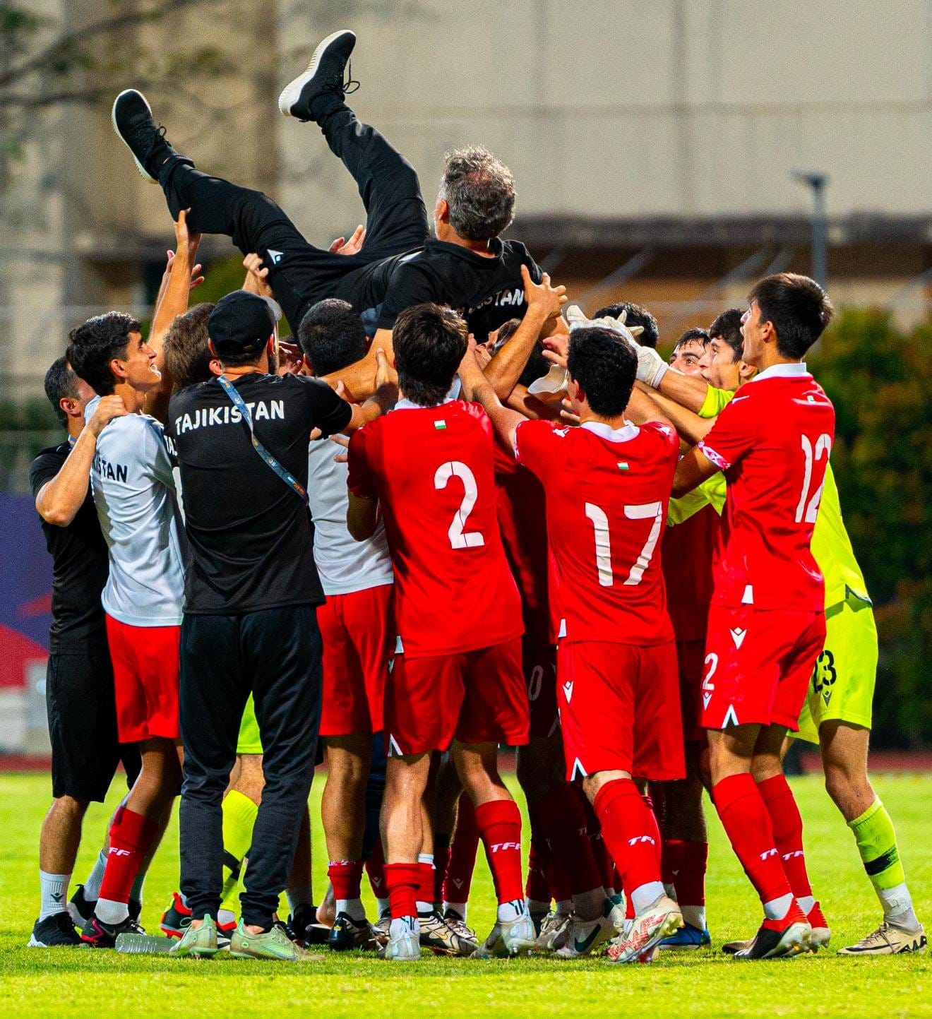 Tajikistan national team players lift Marco Ragini in celebration after qualifying for the 2025 FIFA U17 World Cup