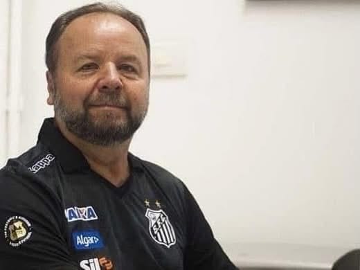 Luiz Greco in a black Santos FC polo shirt, photographed in profile in an indoor setting.
