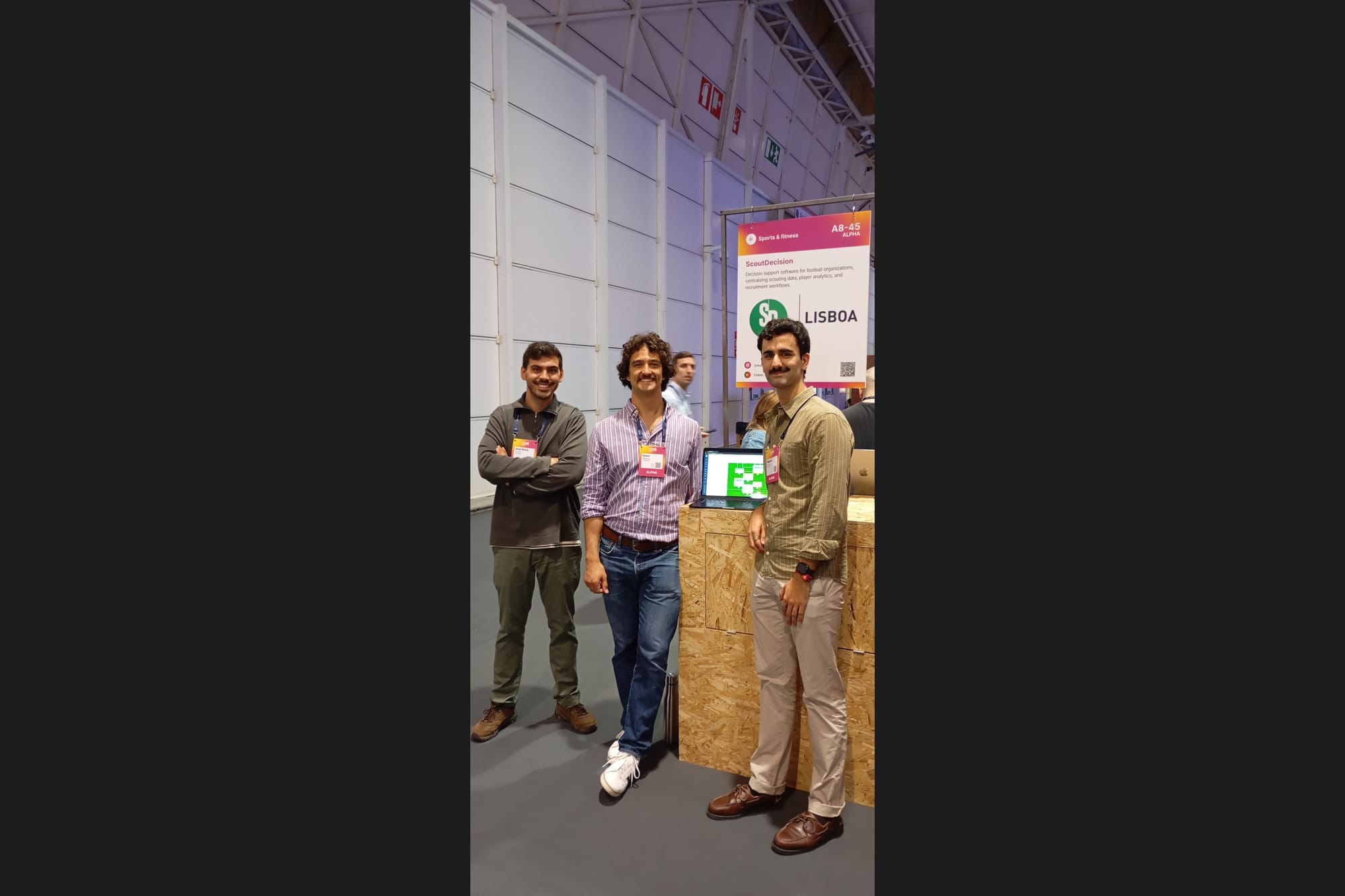 Three members of the ScoutDecision team beside their "Lisboa" stand at Web Summit, with a laptop showing the platform.
