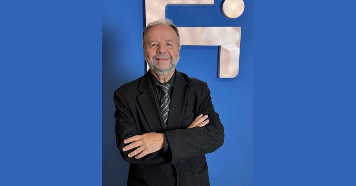 Luiz Greco, Brazilian football director, in a dark suit with arms crossed, before a blue FIFA-style institutional backdrop.