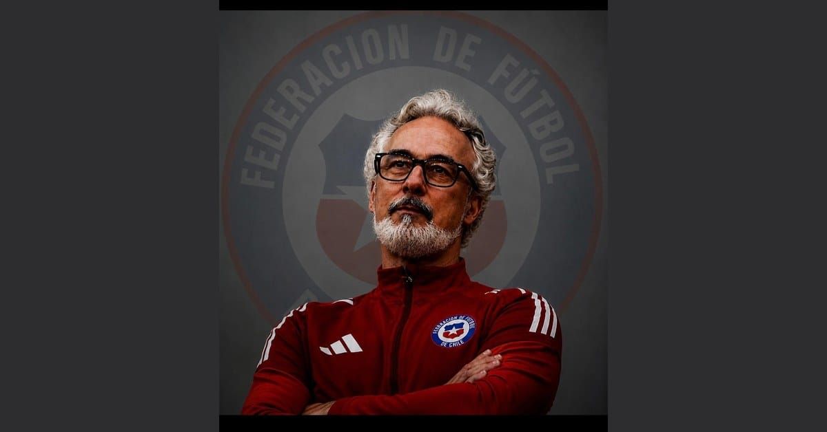 Miguel Torrecilla, Spanish sporting director, with silver curly hair and salt-and-pepper beard, in a red Chilean Football Federation tracksuit with arms crossed.
