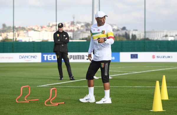 Riedoh Berdien, South African strength and conditioning coach, leading a Mali National Team training session with cones and hurdles on the pitch.