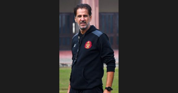 Domingo Oramas, Spanish football coach, in a black club training top, standing outdoors and looking to the side, with a building behind him.