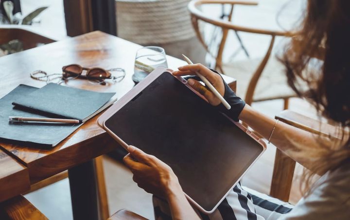 ผู้หญิงใช้การจดบันทึกบน iPad แทนการจดลงในสมุด