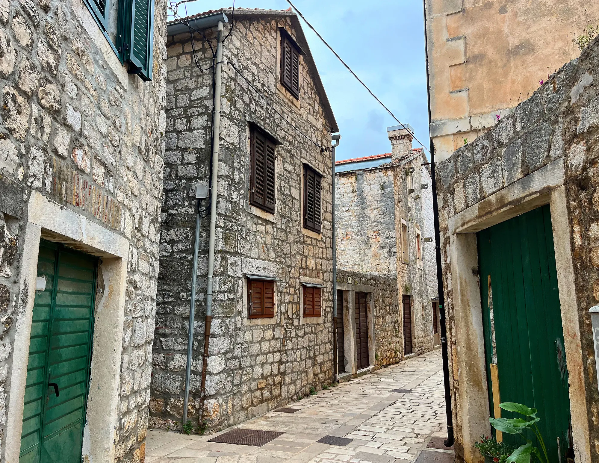 Grey stone street and buildings with green shuttered doors