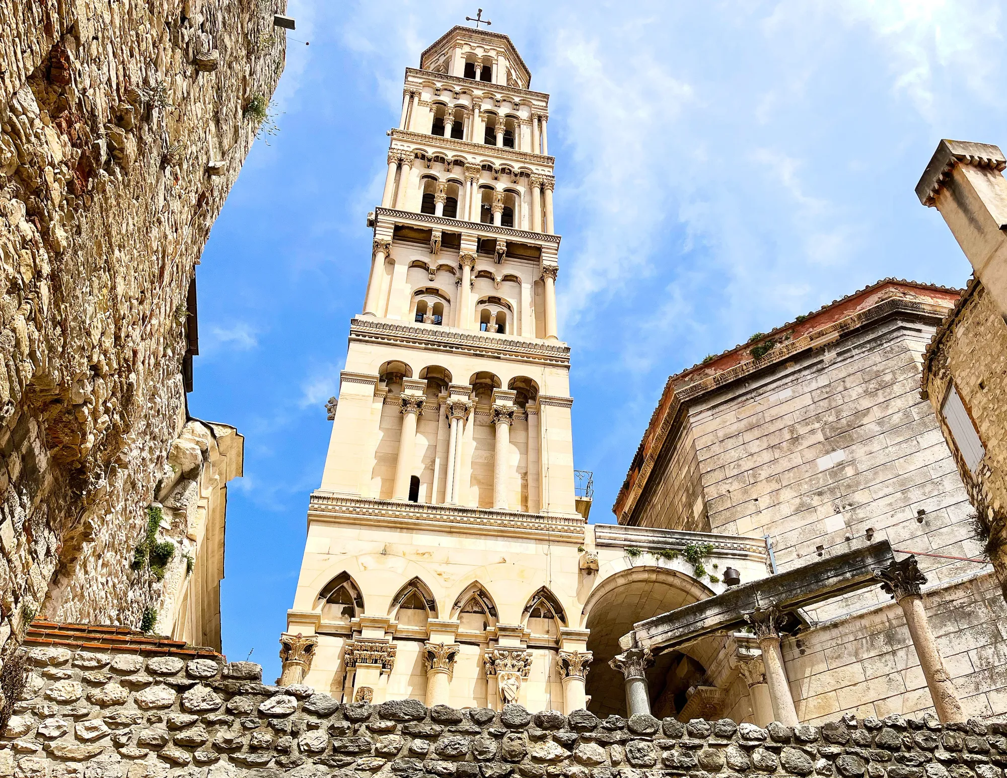 Tan stone tower set amidst darker stone buildings