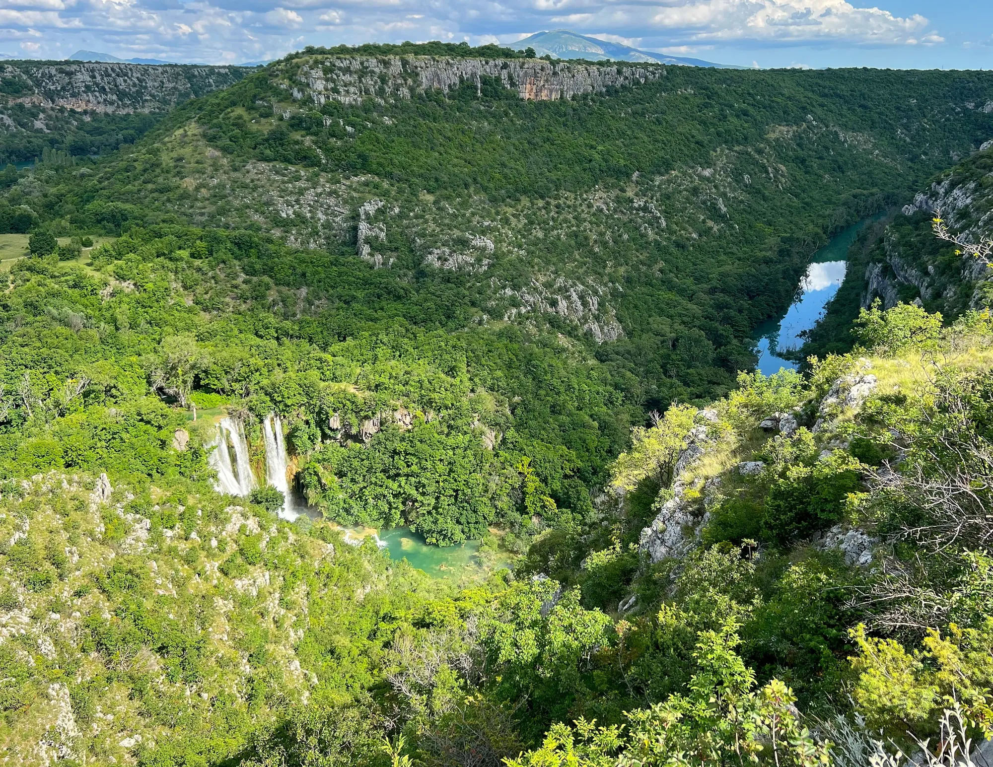 Green valley with a waterfall and reflective lake