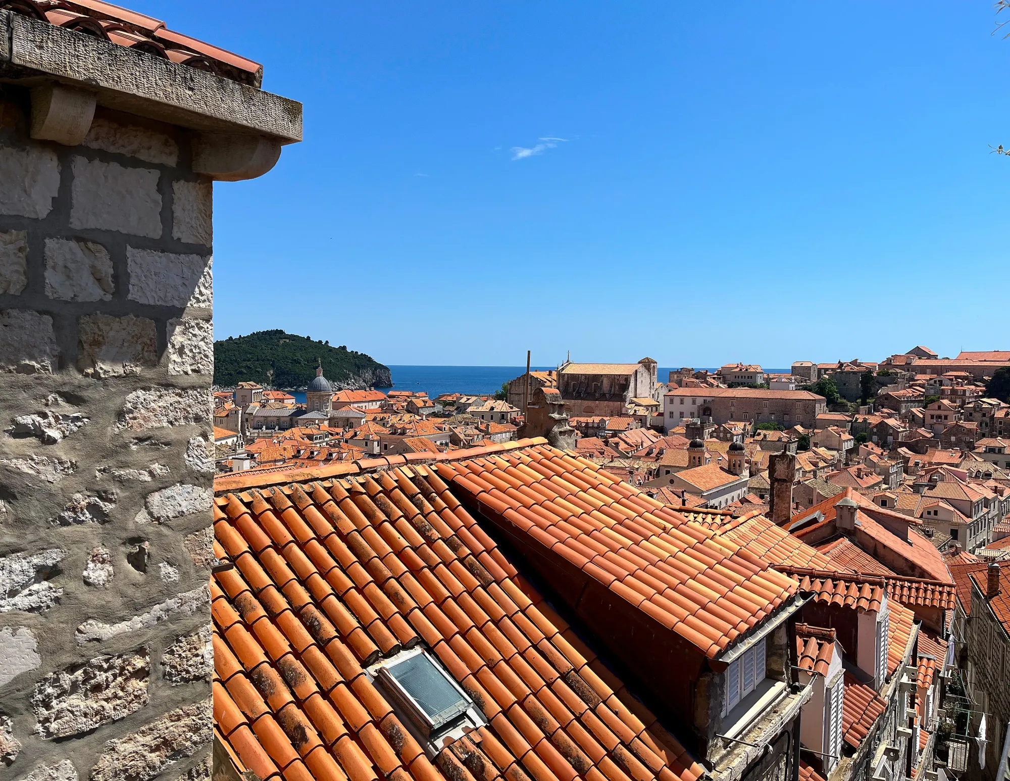 Orange roof tiles across the city looking out over the blue sea