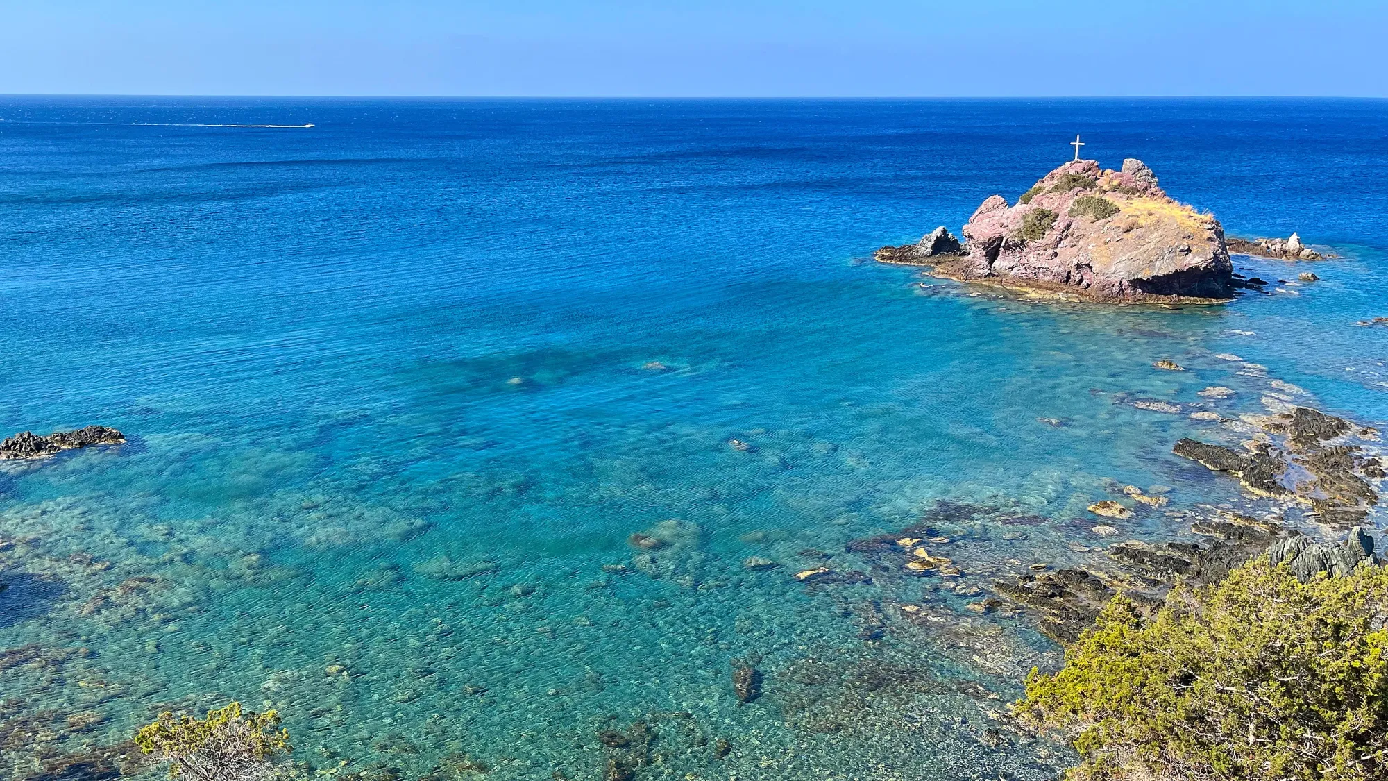 Turquoise ocean floor with coral and a small rock island