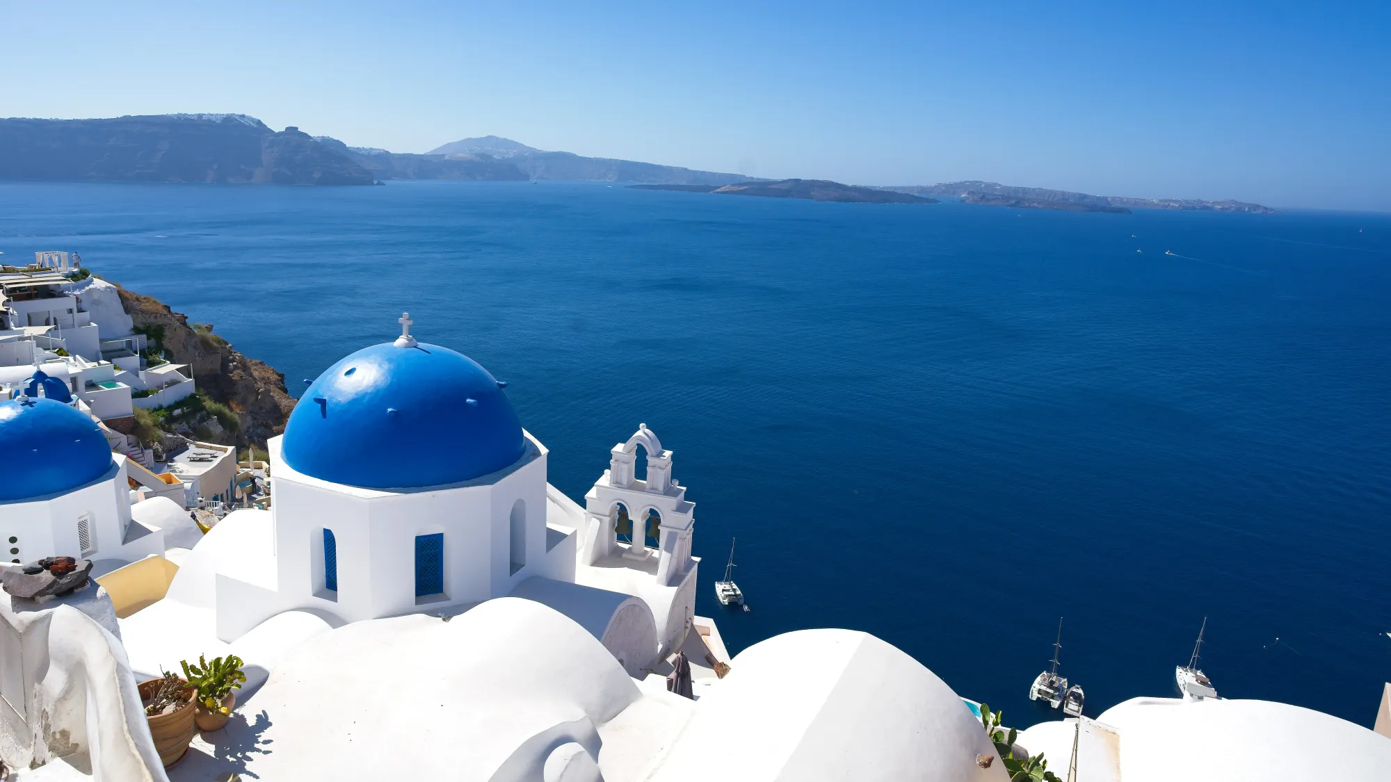 White-washed buildings with blue domes overlooking the blue ocean