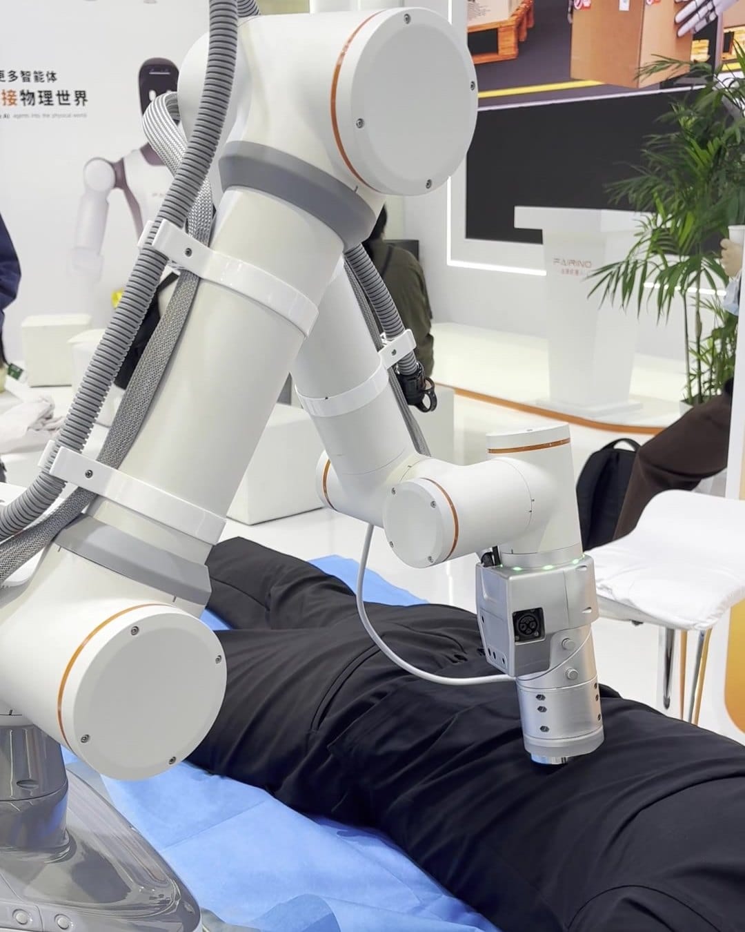 FAIRINO cobot arm with massage head pressing on a visitor's back at CIIF 2026 in Shanghai