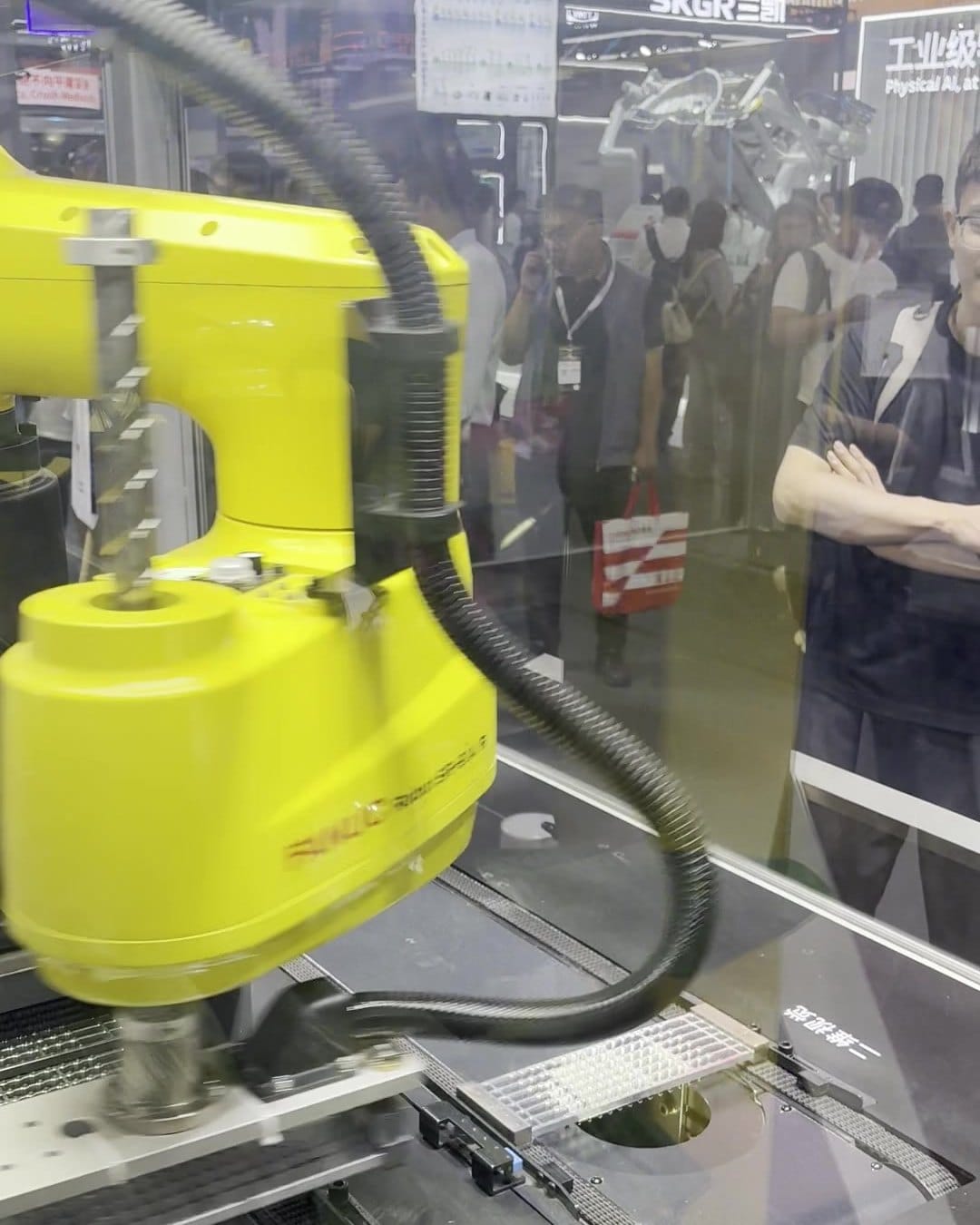 Yellow FANUC SCARA robot behind glass in the international hall at CIIF 2026