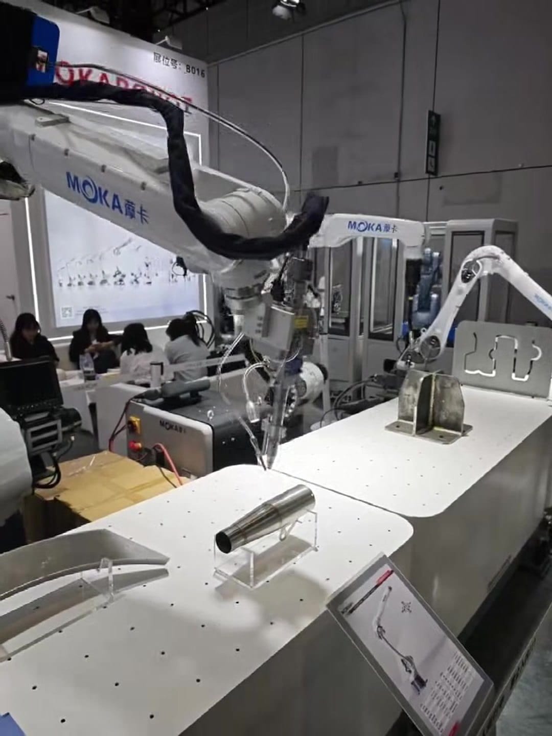 White MOKA robot arms in a metal-parts work cell at CIIF 2026