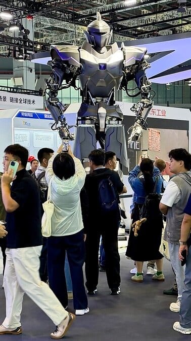 NeodraDynamics Neo1, a four-metre silver humanoid, towers over visitors filming it with phones at the JD Industrial booth at CIIF 2026 in Shanghai