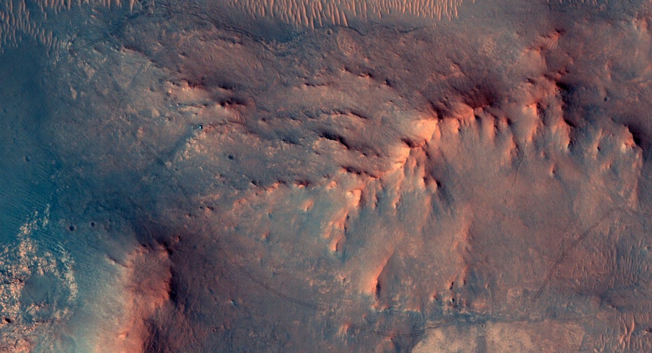 A HiRISE view showing Perseverance as a small green speck on the Martian surface.