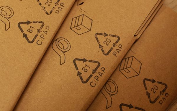 Photo of cardboard boxes with recycling symbols stamped in black ink