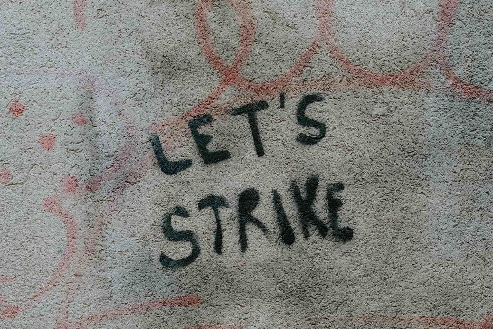 Photo of graffiti on a wall reading "let’s strike"