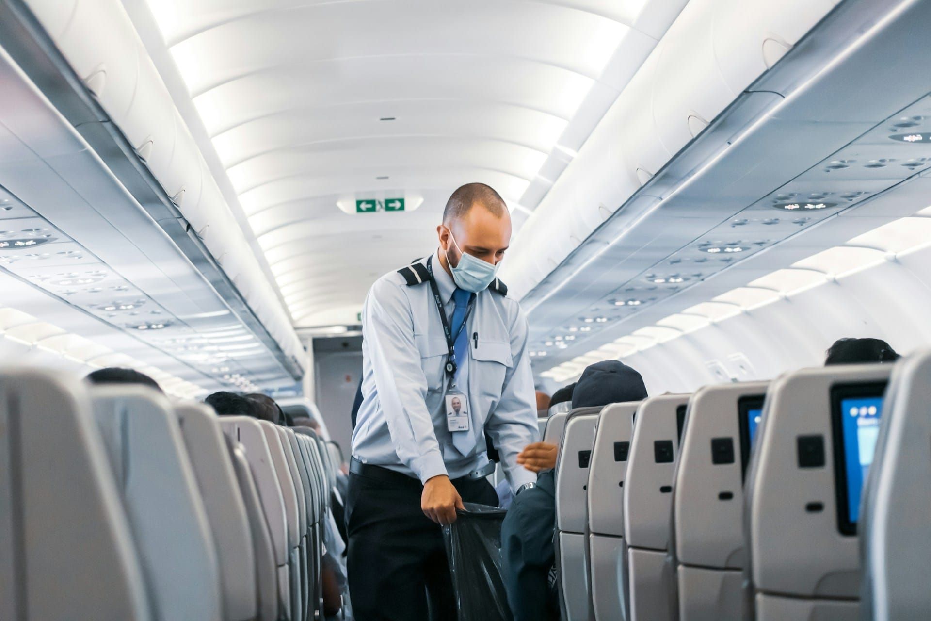 A flight attendant collects trash on a flight