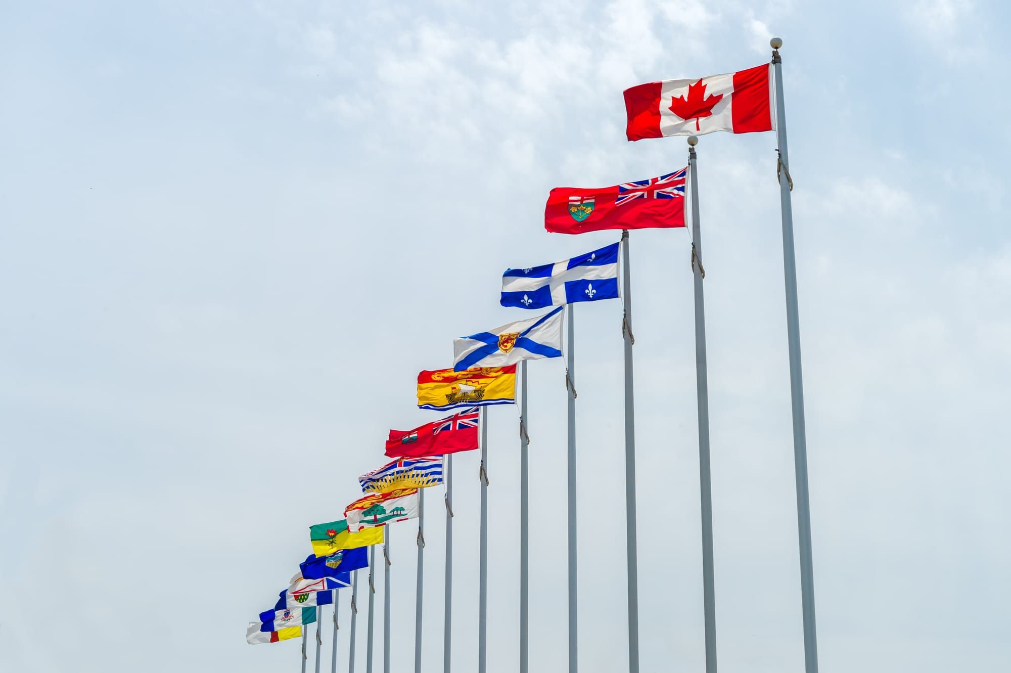 The flags of Canada's provinces and territories flying on flagpoles
