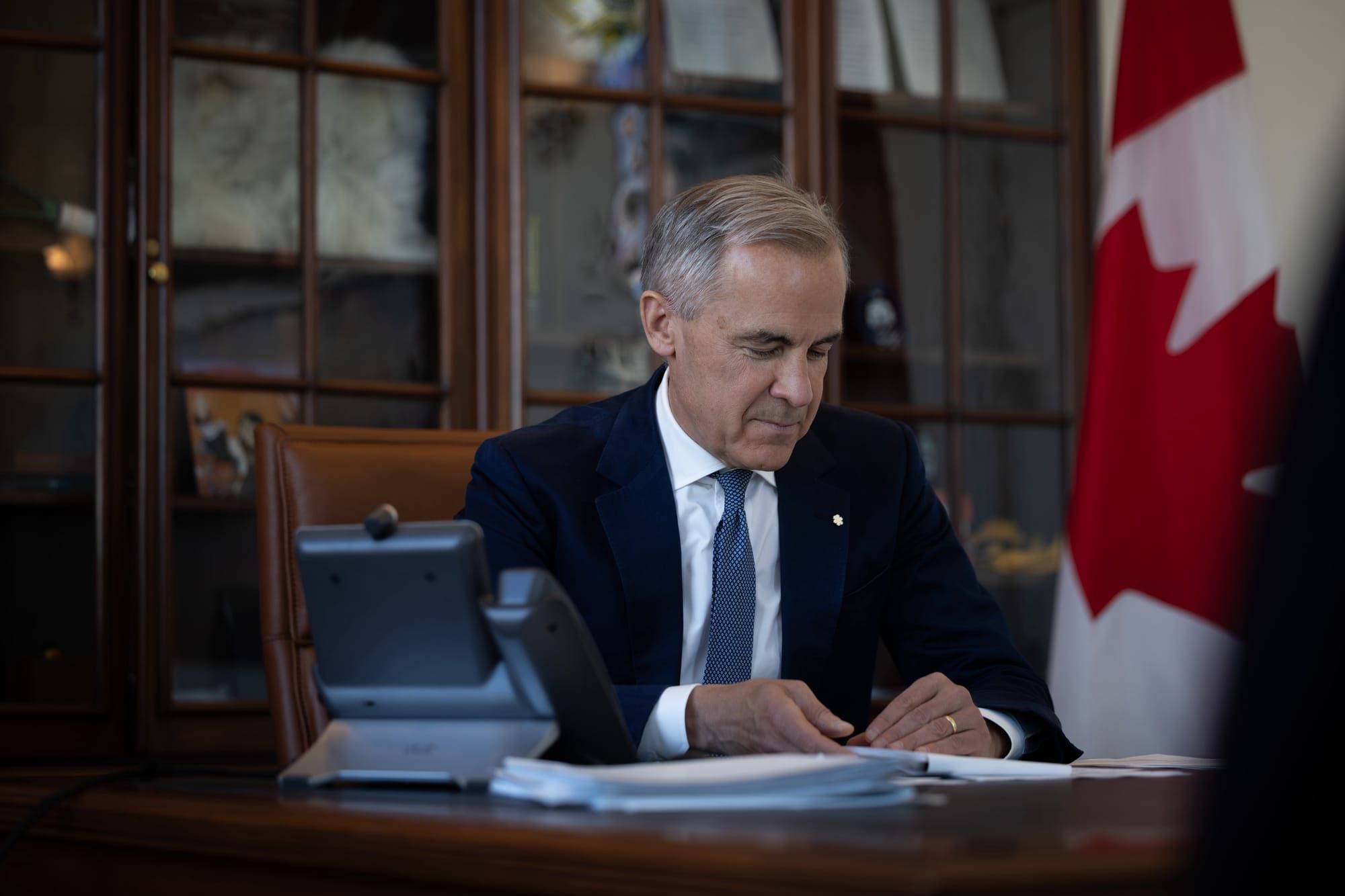 A photo of Prime Minister Mark Carney sitting at his desk.