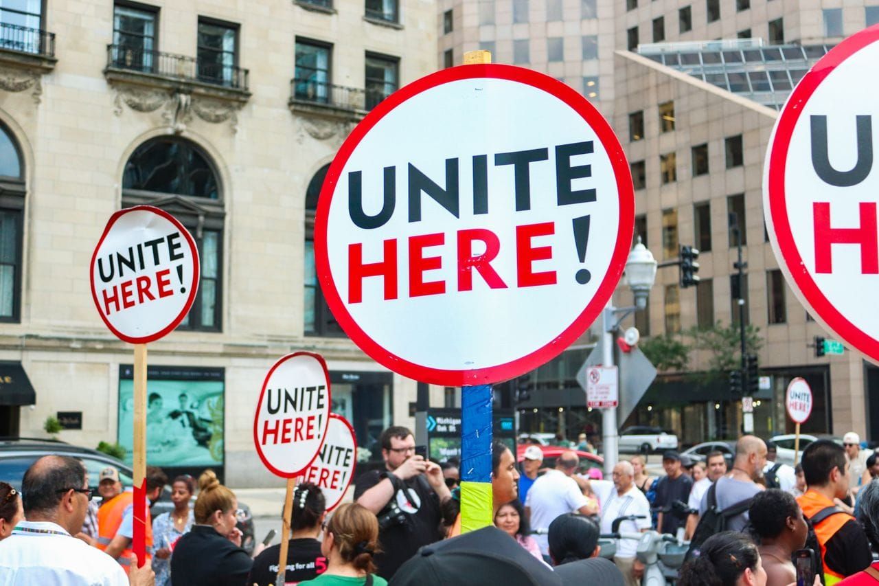 Protesters holding signs reading "Unite Here!"