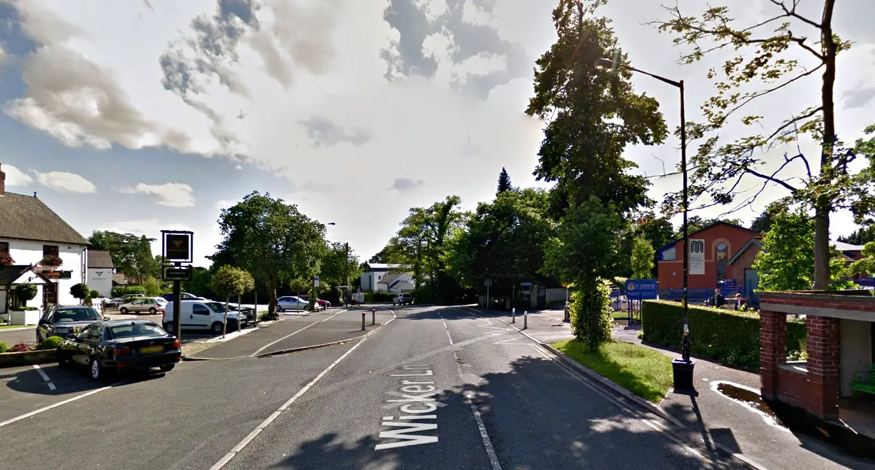 A school crossing patrol helps schoolboys across the road outside St Ambrose College