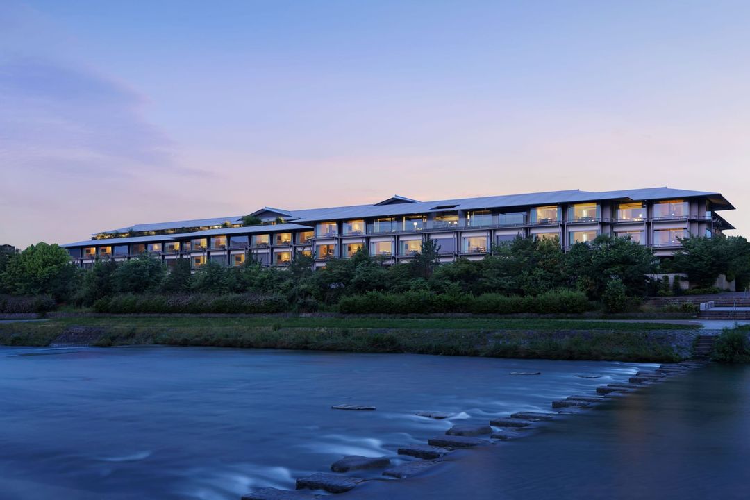 The Ritz-Carlton, Kyoto across the Kamogawa river at dusk, with stepping stones in the foreground