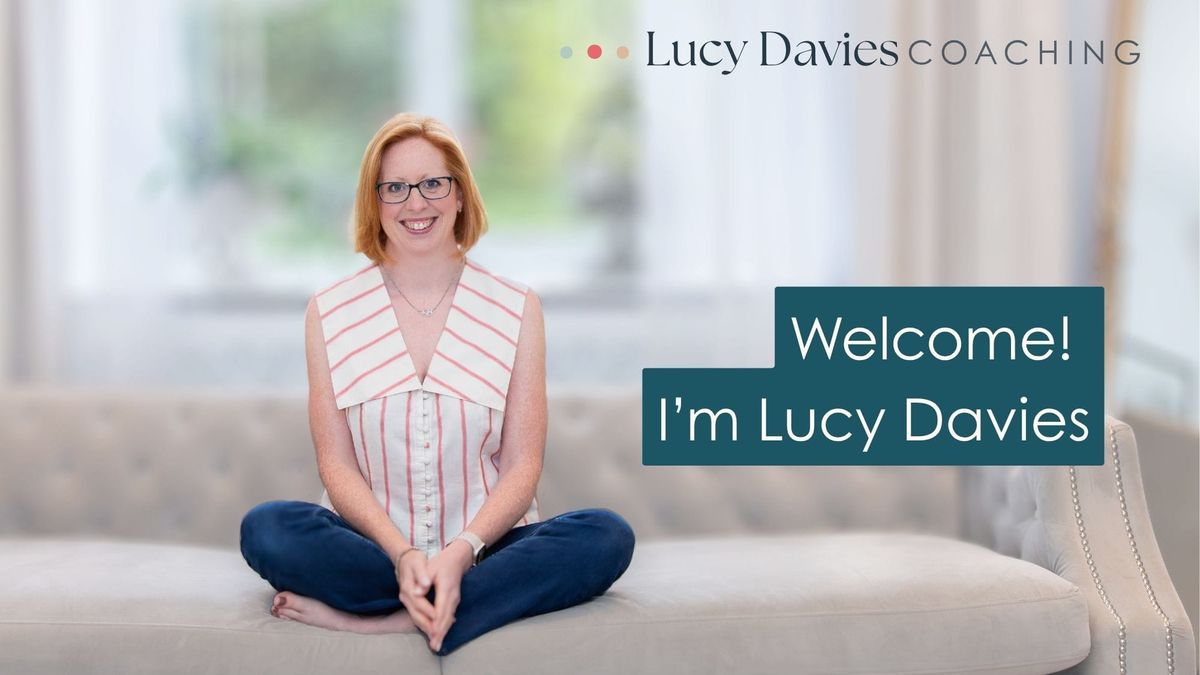 Photo of Lucy Davies - a red-haired woman sitting on a grey sofa