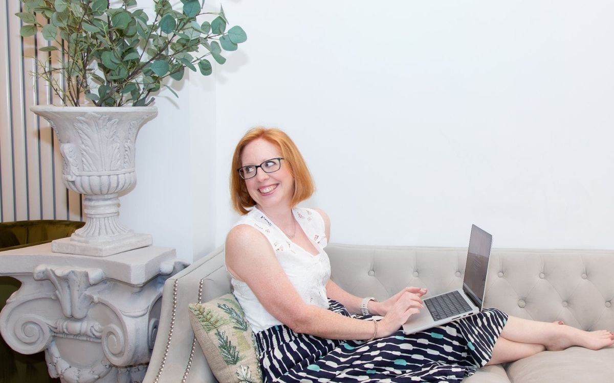 Lucy Davies, business coach, in a striped sleeveless top looking down at a floral notebook