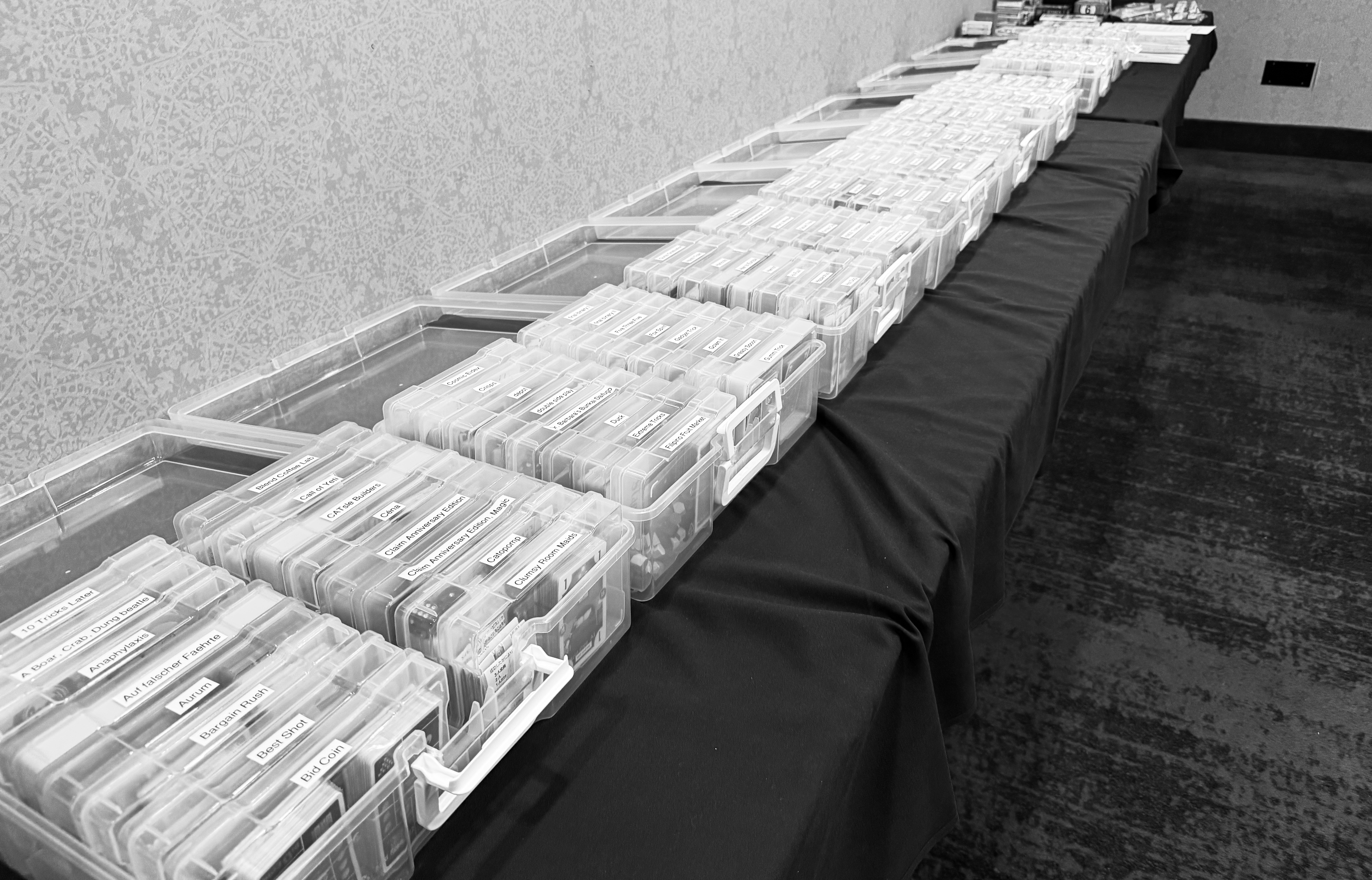 Games in plastic boxes lined up on a table. There are roughly 80 to 100 games visible.