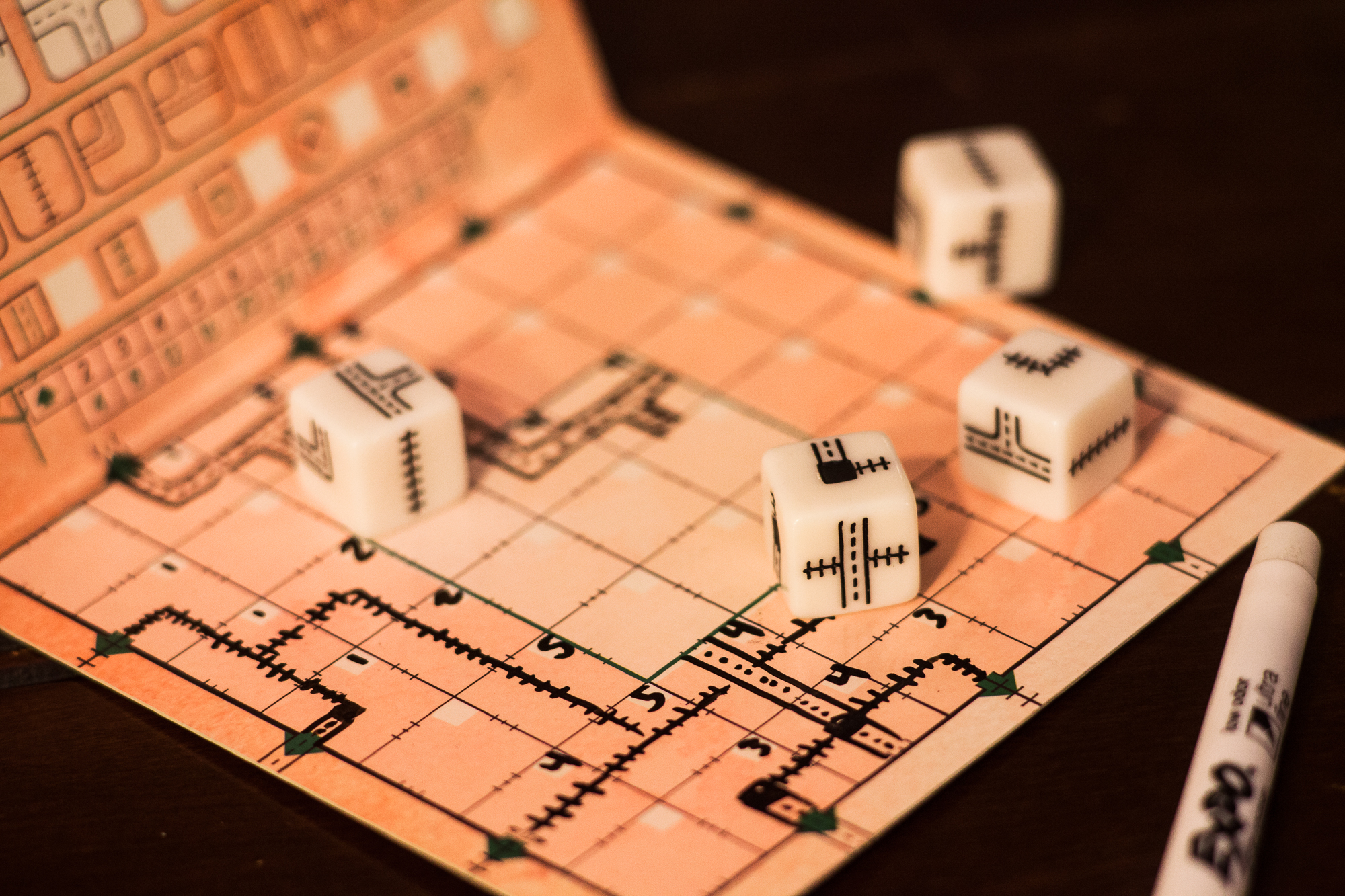 Dice from the game Railroad Ink on a player board. The board has several markings on it indicating routes.